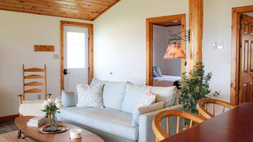 A cozy living room with a light blue sofa, wooden chairs, a coffee table, and a wooden ceiling.
