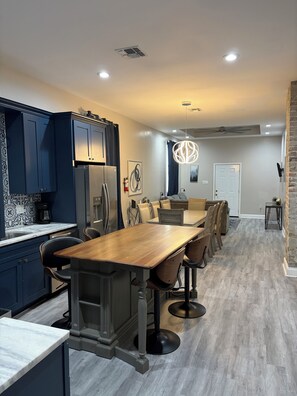 Una cucina moderna con mobili blu scuro, un tavolo da pranzo in legno e un lampadario.