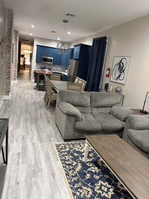Un soggiorno moderno con un divano grigio, un tavolino in legno e un tappeto decorato.