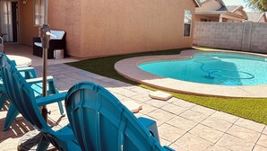 A backyard with a swimming pool, blue chairs, and a patio umbrella. - Avondale Retreat with Pool near Stadium, Top Golf and Spring Training (Avondale)