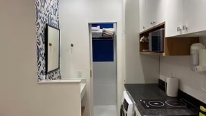 Kompakti keittiö, jossa on sisäänrakennettu liesi, mikroaaltouuni ja pieni työtaso.
