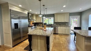 Una cocina moderna con una isla central, electrodomésticos de acero inoxidable e iluminación colgante.
