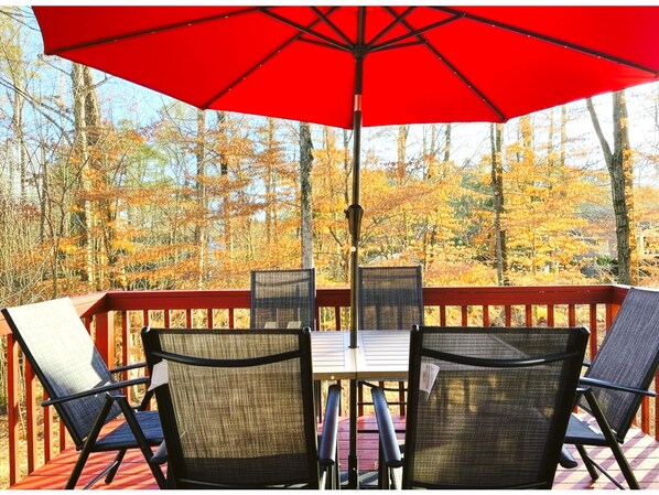 A deck with a red umbrella, four chairs, and a table. - King Bed, Workspace, Games near RDU, RTP, Downtown (Raleigh)