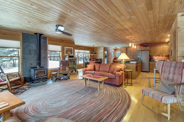 Un intérieur de chalet chaleureux avec une cheminée, des meubles en bois et un coin cuisine.