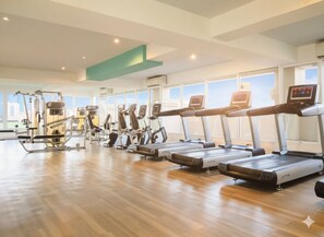 Un gimnasio con cintas de correr, elípticas y equipo de pesas.