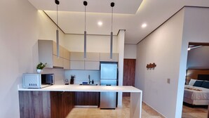 Cocina moderna con una isla central, microondas y un lavabo. Hay tres sillas tapizadas frente a la isla.