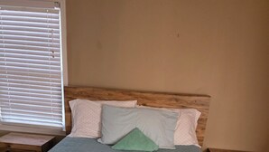 Una cama con colcha estampada, dos almohadas y cabecera de madera.