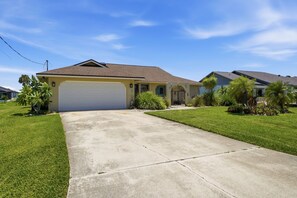 A residential house with a garage, a driveway, and a well-maintained lawn. - Canal-Front Pool Home Near Gulf Beaches & Golf (Rotonda West)