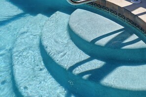 A clear pool with a stone edge and a metal ladder. - Canal-Front Pool Home Near Gulf Beaches & Golf (Rotonda West)
