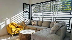 A modern living room with a sectional sofa, a yellow armchair, and a round coffee table.