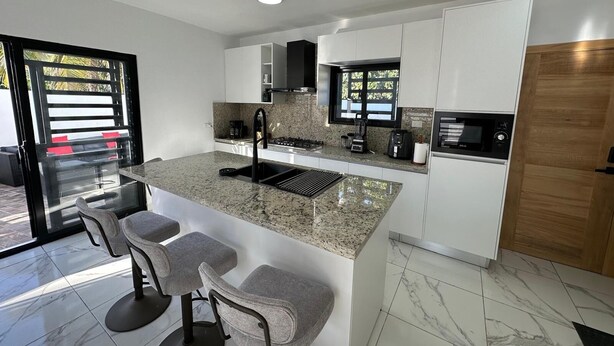 A modern kitchen with a granite countertop, stainless steel appliances, and a large island with bar stools.