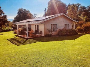 A single-story house with a covered porch, a small lawn, and a garden area. - Swannie Creek - Private Hot Tub Retreat in the Elgin Valley! (Grabouw)