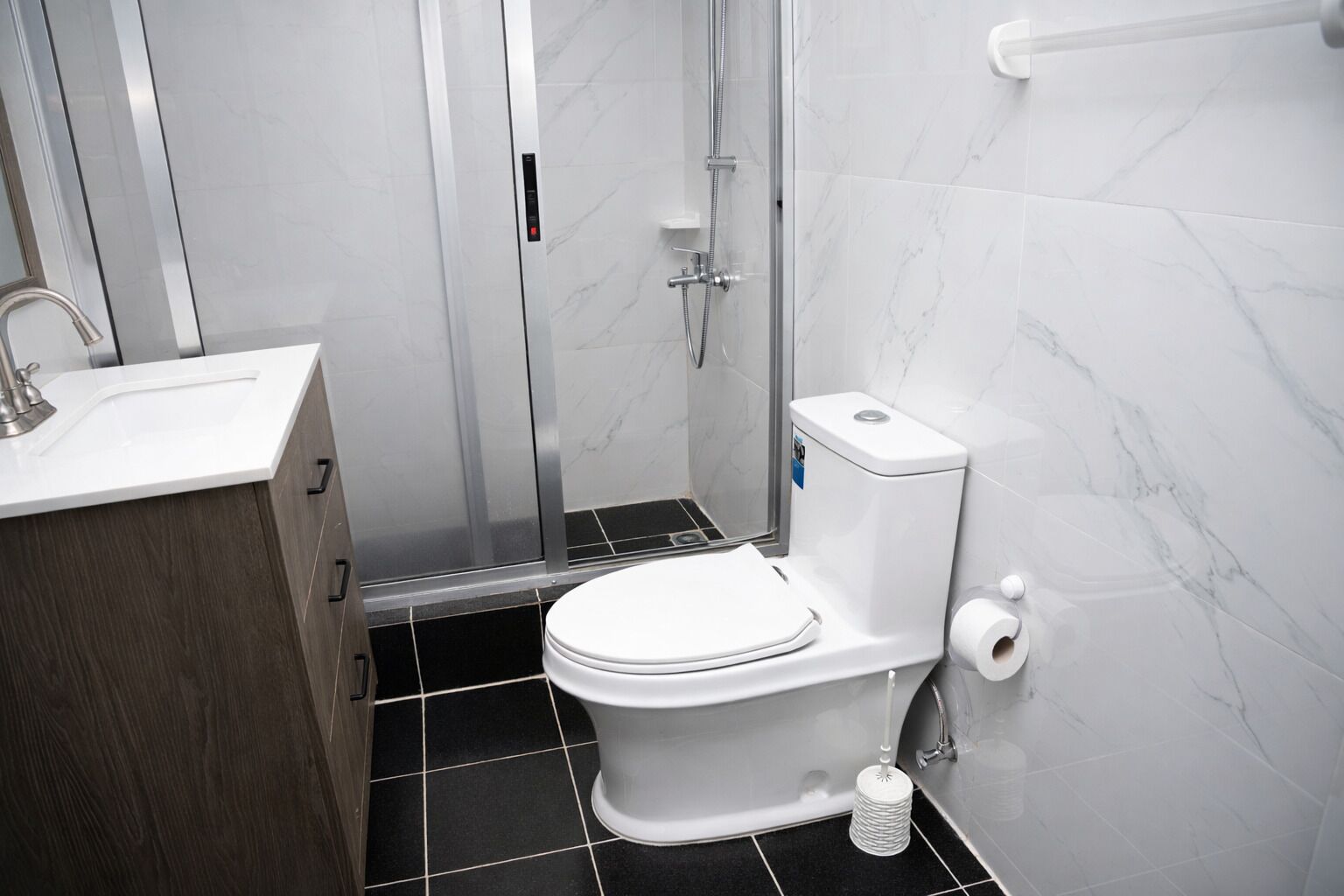 A modern bathroom with a toilet, shower, and sink.