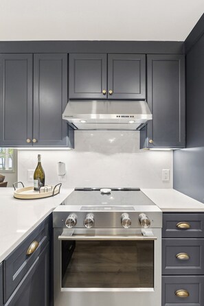 A kitchen with dark cabinets, a stainless steel range hood, and a built-in oven.