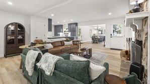 Uma sala de estar espaçosa, com um sofá verde, um sofá de couro marrom e uma mesa de centro de madeira.