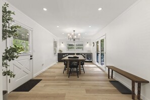 A modern kitchen with a dining table and chairs, a bench, and a view of the outdoors.