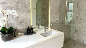 A modern bathroom with a white vanity, a large mirror, and a glass shower enclosure. - Portsea Paramount - when only the best will do! (Portsea)
