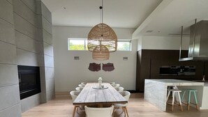 A modern kitchen with a central island, a dining table with chairs, and a hanging light fixture. - Portsea Paramount - when only the best will do! (Portsea)
