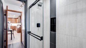 Une salle de bain moderne avec une porte de douche en verre, un porte-serviettes noir et une pomme de douche bien visible.