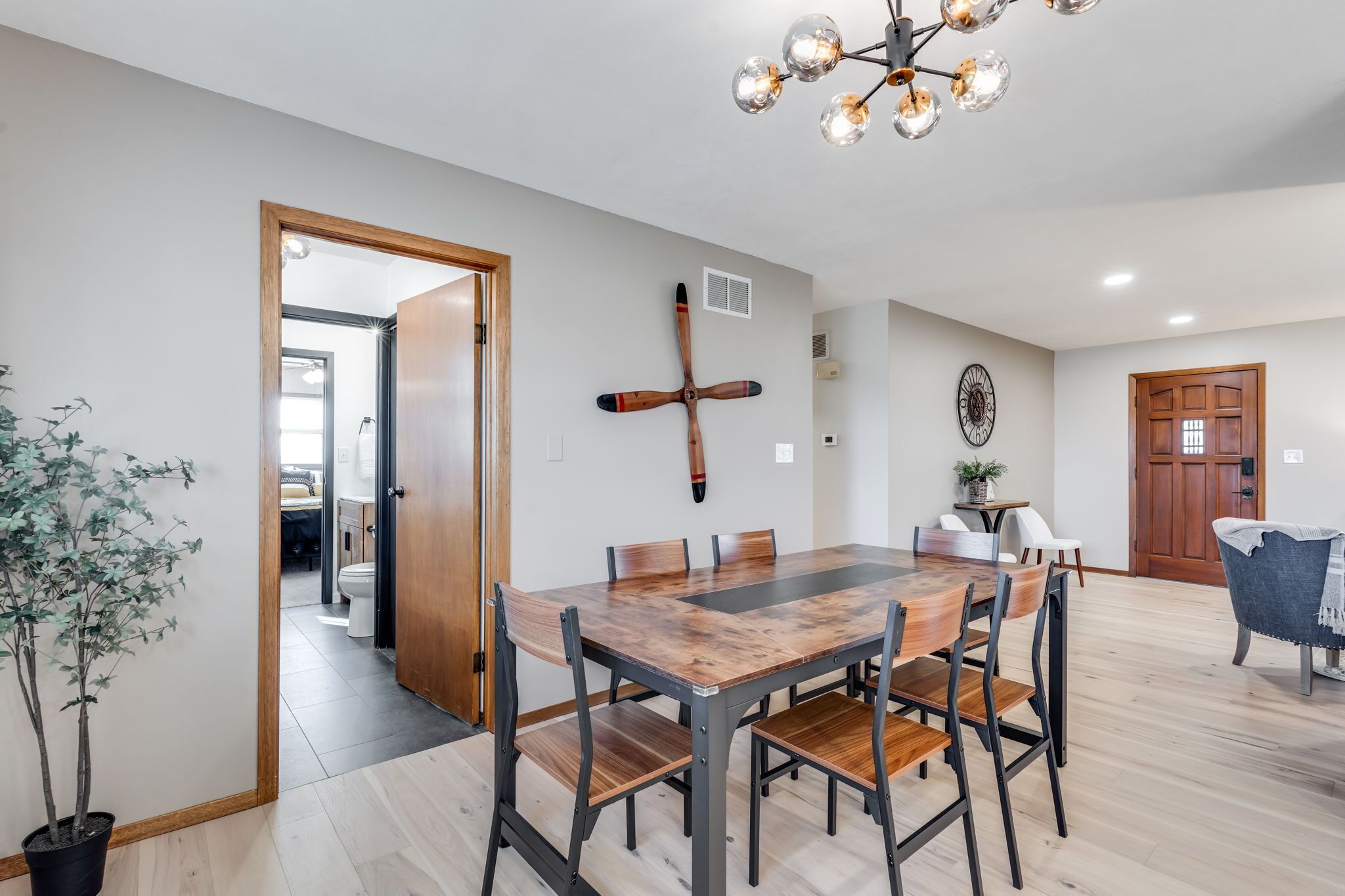 Un coin repas avec une table et des chaises en bois, un luminaire au plafond et une plante en pot.
