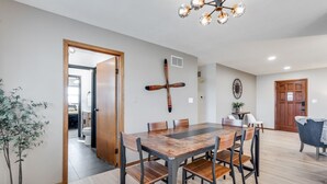 Un coin repas avec une table et des chaises en bois, un luminaire au plafond et une plante en pot.
