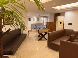 A modern living room with a foosball table, sofas, and a large plant.