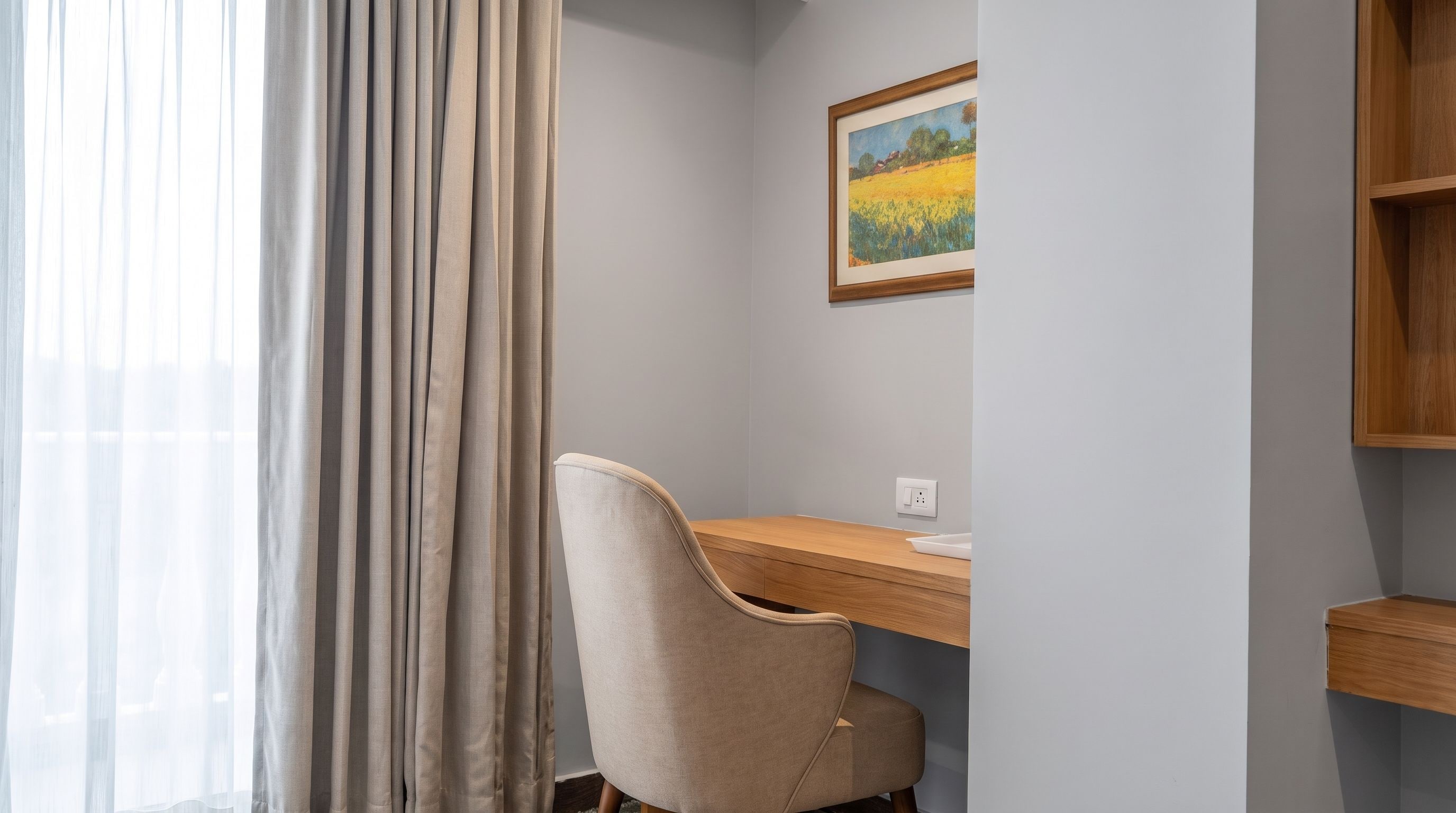 Een kamer met een bureau, stoel en een schilderij aan de muur.