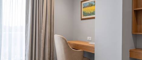 Een kamer met een bureau, stoel en een schilderij aan de muur.