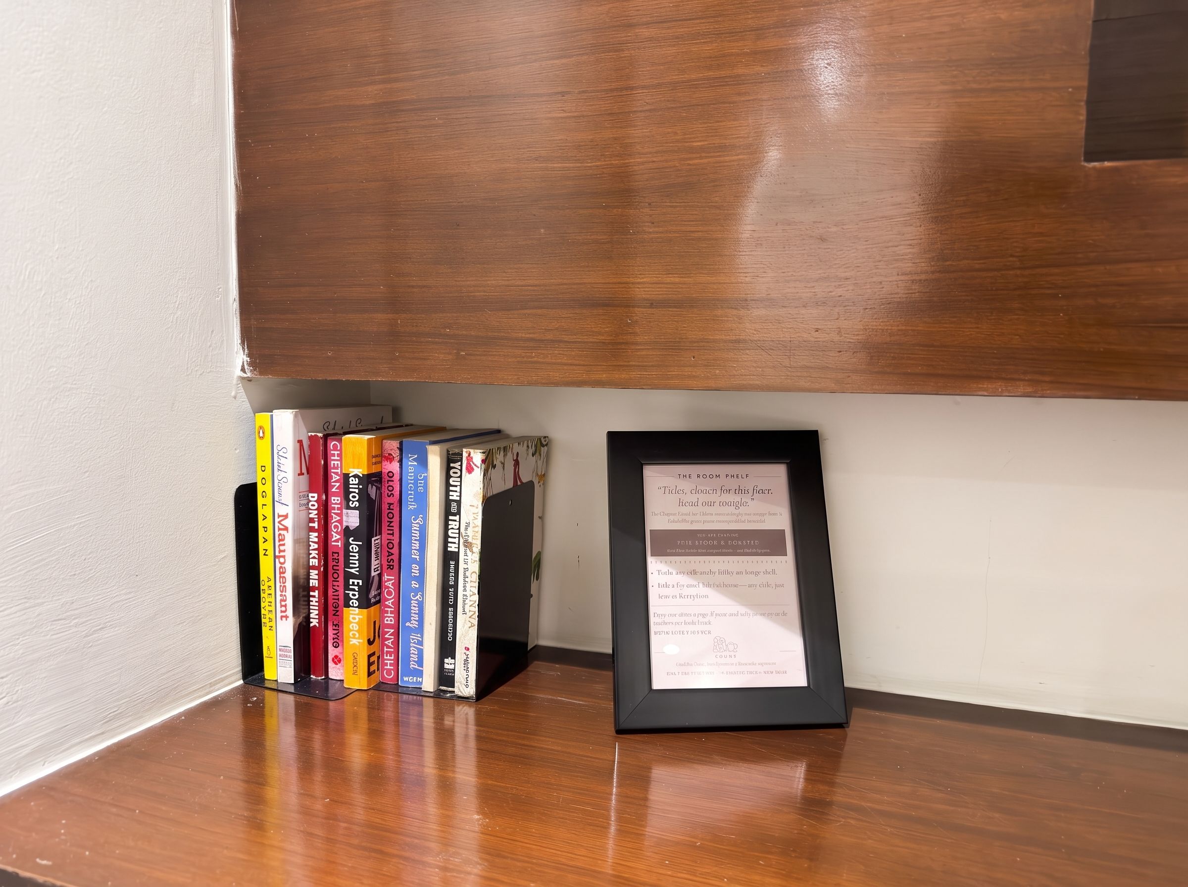 A bookshelf with a framed quote on a wooden table.