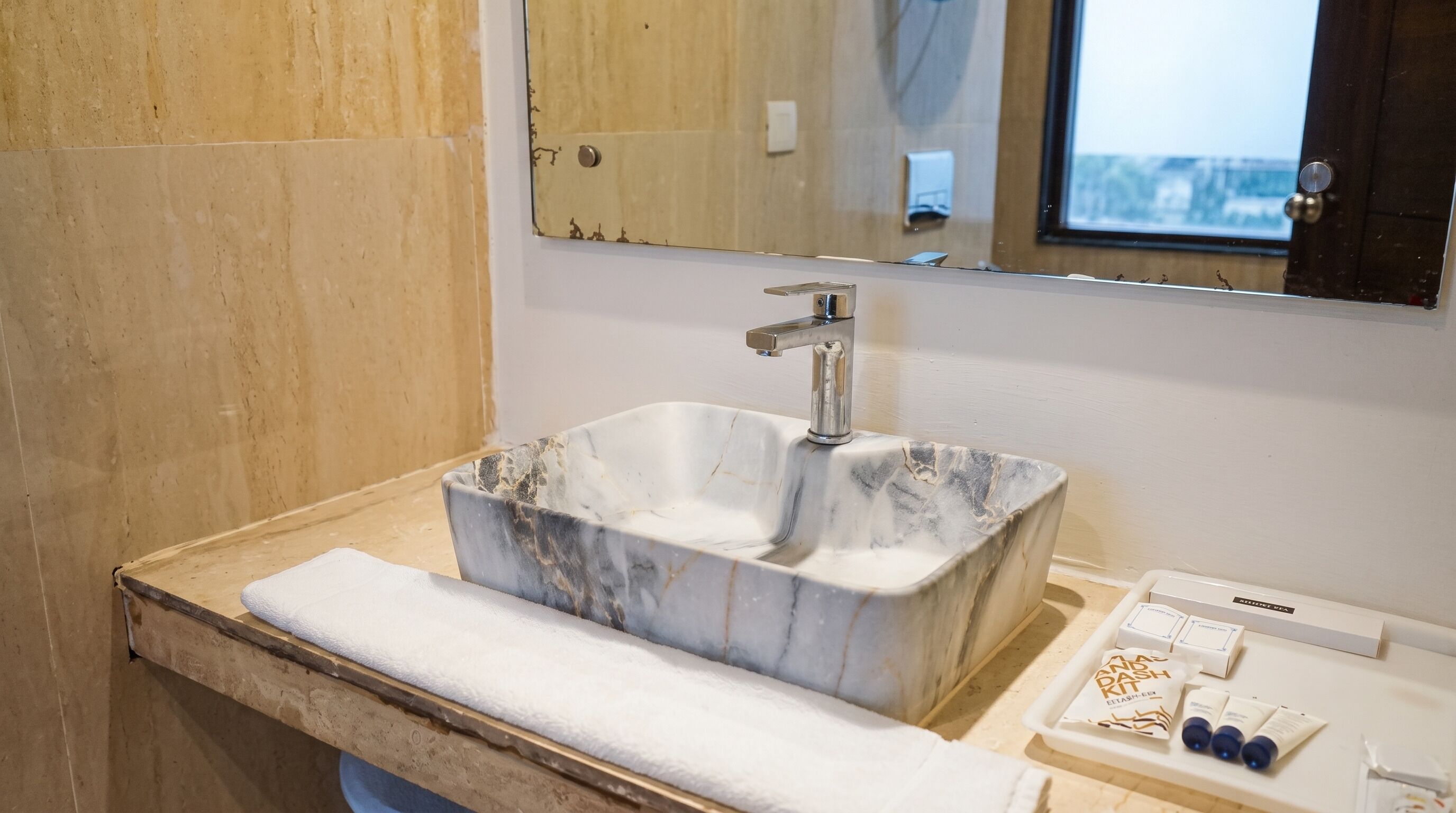Un bagno con lavabo in marmo, un asciugamano e un mobile contenitore con articoli da toilette.