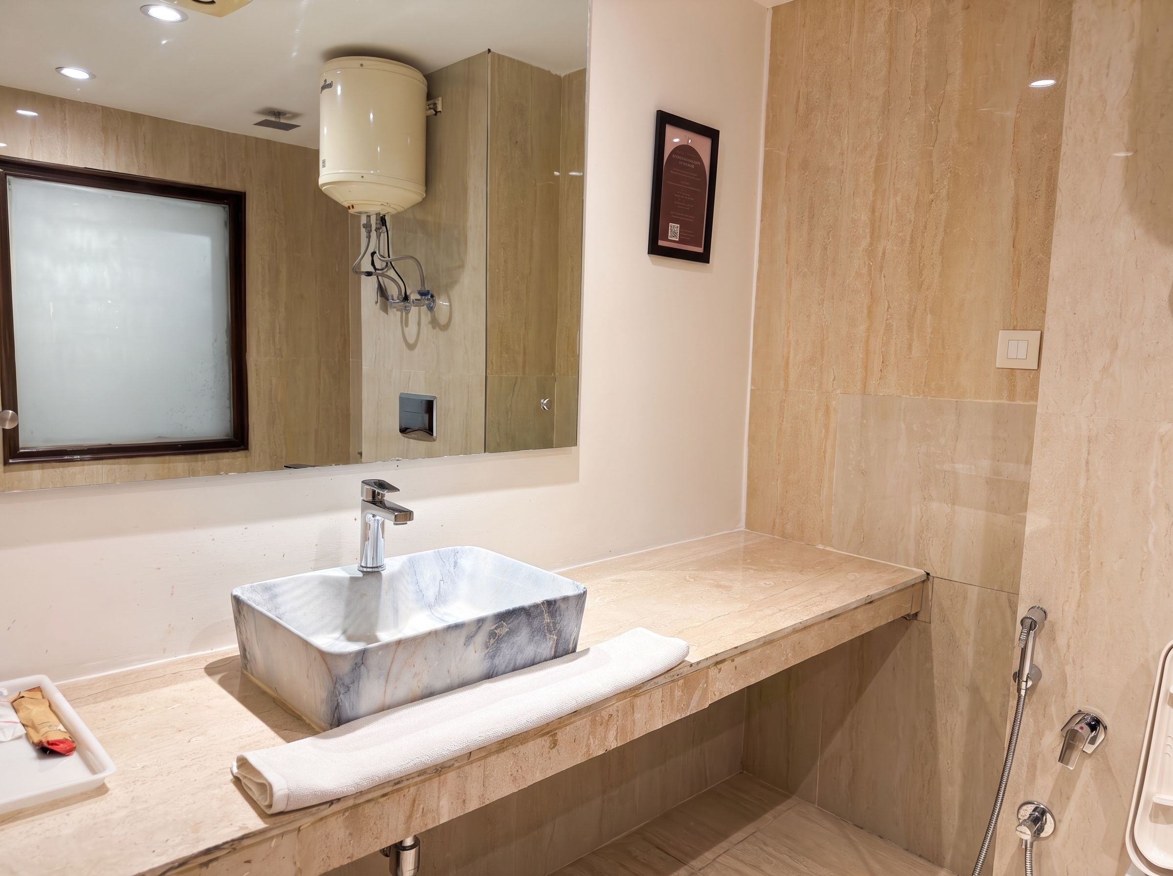 A bathroom with a marble sink, a towel, a shower, and a mirror.