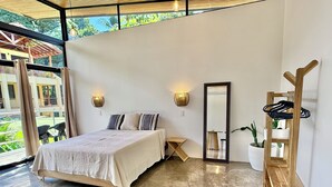 A modern bedroom with a large bed, a wooden side table, a mirror, and a potted plant. - New studio in awesome Dominical walk to the beach in center of town, security AC (Dominical)
