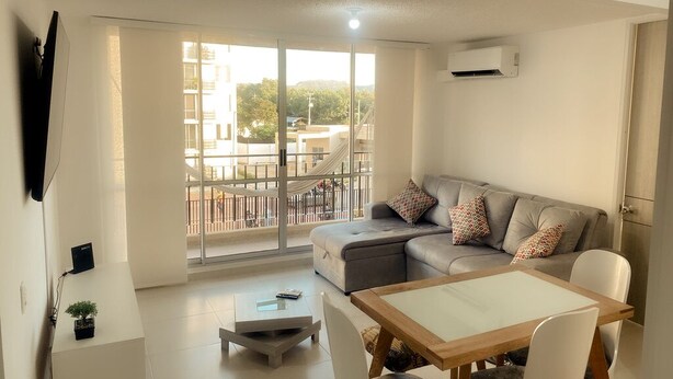 A modern living room with a sofa, a dining table, and a TV. - Cozy 2-bedroom apartment in gorgeous Ricaurte with AC and gym (Ricaurte)