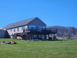 A two-story house with a balcony and a covered porch. - Tiki on the Lake! Charming 4 bedroom, 2 acre home on Waneta Lake, Finger Lakes! (Hammondsport)