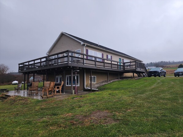 A two-story building with a balcony and a covered outdoor seating area. - Tiki on the Lake! Charming 4 bedroom, 2 acre home on Waneta Lake, Finger Lakes! (Hammondsport)
