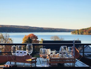 A table set with wine glasses and bottles, overlooking a lake with autumn foliage. - Tiki on the Lake! Charming 4 bedroom, 2 acre home on Waneta Lake, Finger Lakes! (Hammondsport)