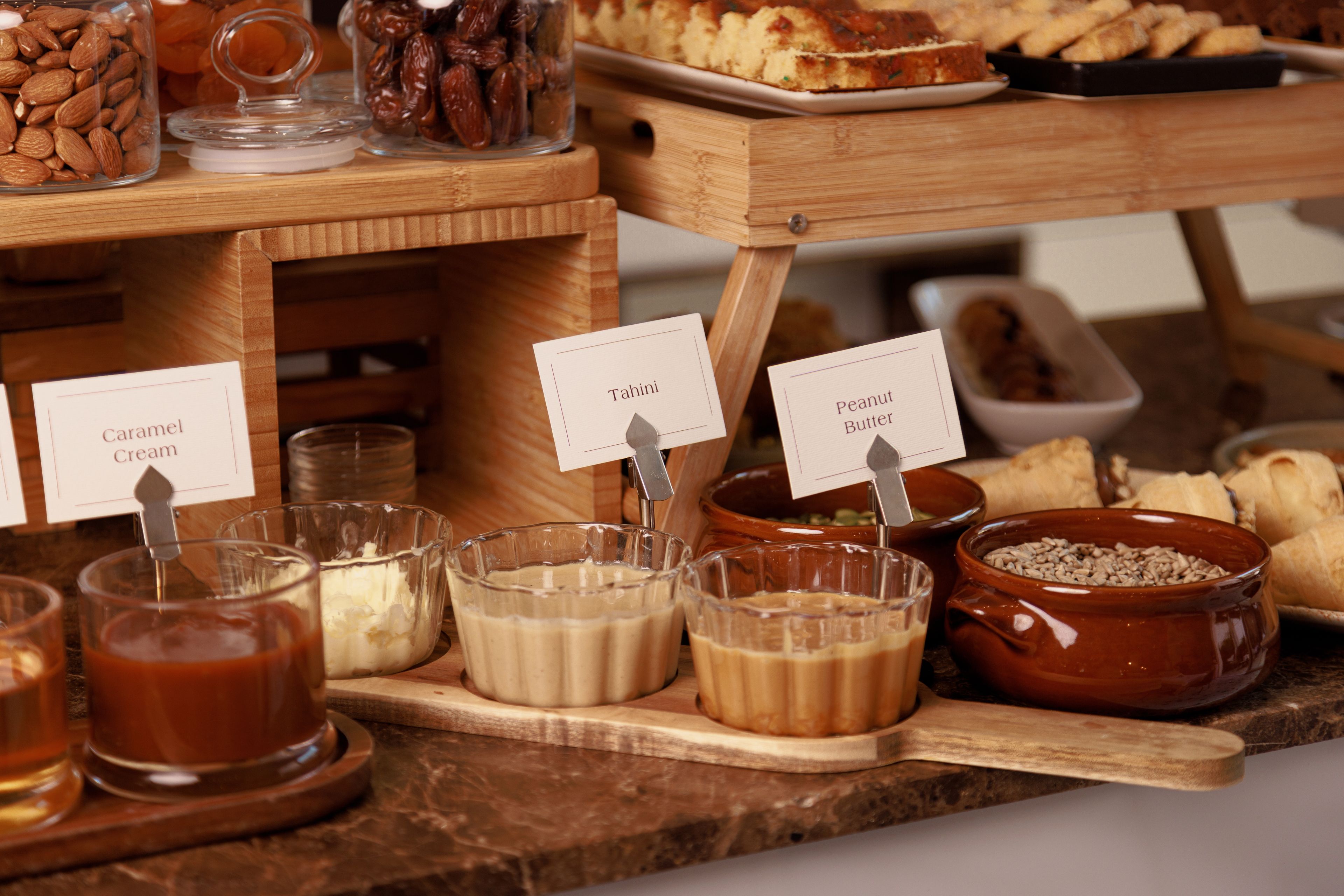 Un buffet proposant une variété de plats et d’étiquettes, notamment « Tahini », « Crème caramel » et « Beurre de cacahuète ».