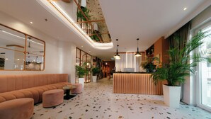 Um hall de hotel moderno com balcão de recepção, área de estar e grandes janelas.