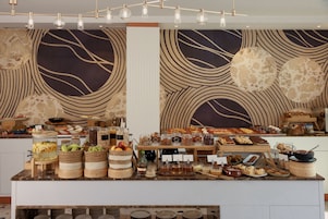 Un buffet proposant une variété d’aliments et de boissons, notamment des fruits, des noix et des desserts.