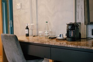 A kitchen counter with a coffee maker, wine bottle, glasses, and a water bottle. - Moenia Boutique Hotel (Durrës)