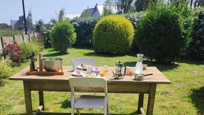 Un conjunto de mesa y sillas de picnic de madera dispuesto al aire libre, con diversos alimentos para el desayuno.