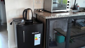 Une petite cuisine équipée d’un réfrigérateur Whirlpool, d’une machine à café, d’un four à micro-ondes et d’un évier.
