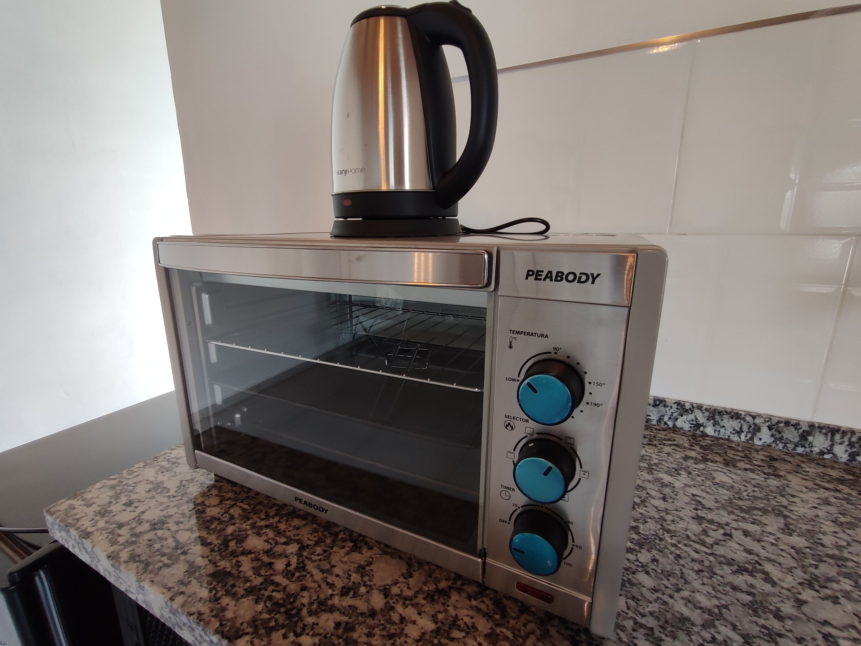 A kitchen with a stainless steel toaster oven labeled "PEABODY" on a granite countertop.