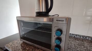 A kitchen with a stainless steel toaster oven labeled "PEABODY" on a granite countertop.