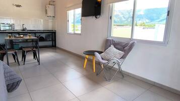 A spacious living area with a kitchen, a dining table, and a comfortable chair.