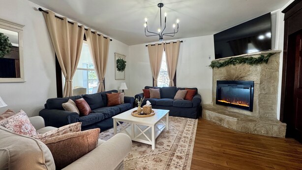 Ein Wohnzimmer mit Kamin, zwei Sofas, einem Couchtisch und einem gemusterten Teppich.