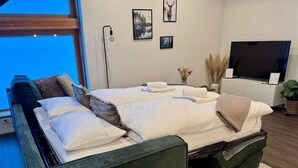 Et moderne hotelværelse med en stor seng, en sofa, et fladskærms-tv og havudsigt.