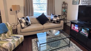 Ein Wohnzimmer mit einer Couch, einem Couchtisch, einer TV-Kommode und einem Bücherregal.