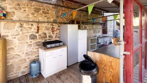 A rustic kitchen with a stone wall, a gas stove, a white cabinet, and a wooden counter.