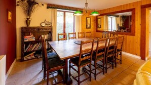 A dining area with a wooden table and chairs, a bookshelf, and a mirror.